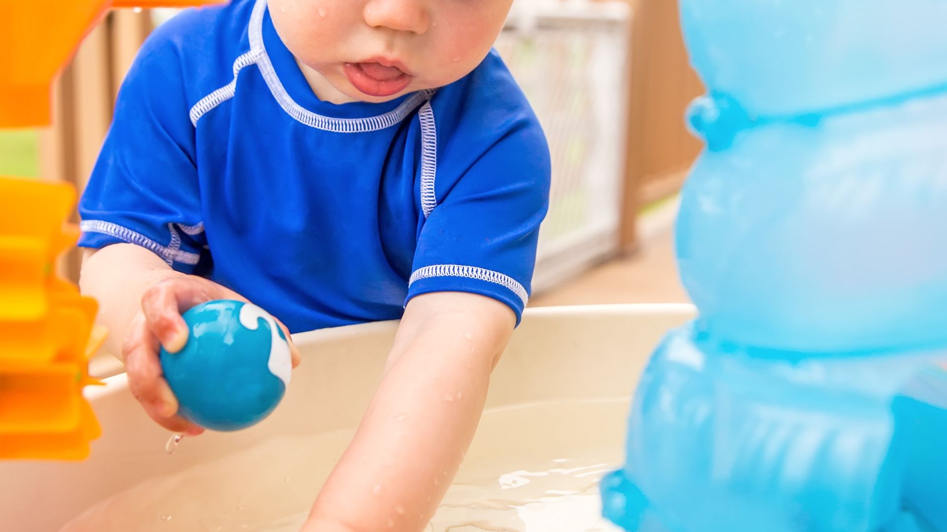 water play for toddlers holding a ball using a water table